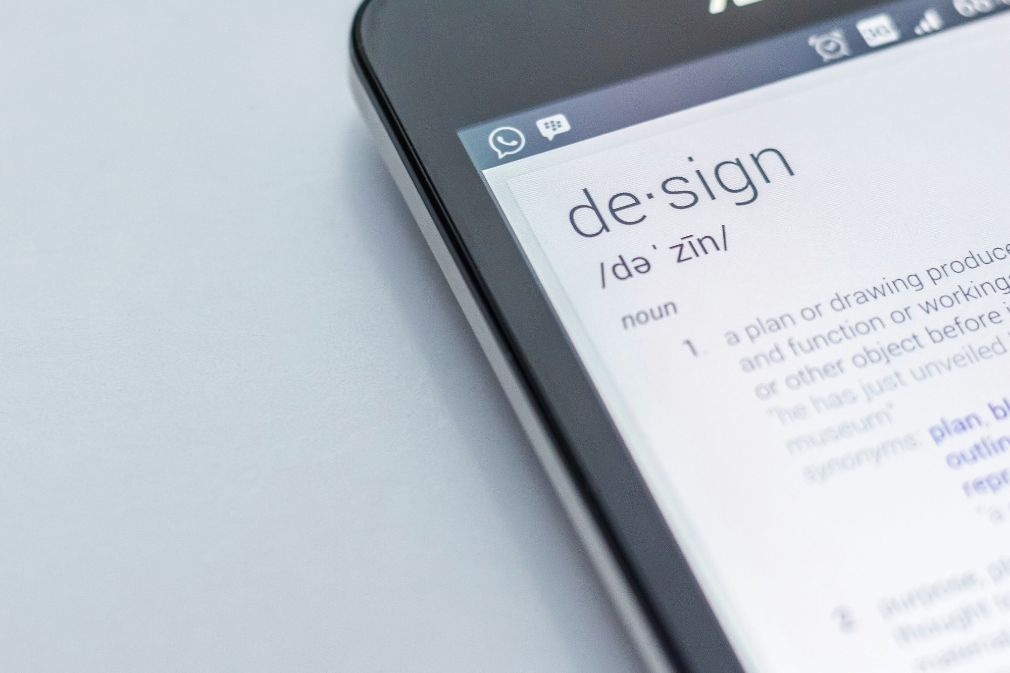 Close-up of a smart device screen showing the word 'design' and its definition, symbolizing purposeful and values-driven creativity.